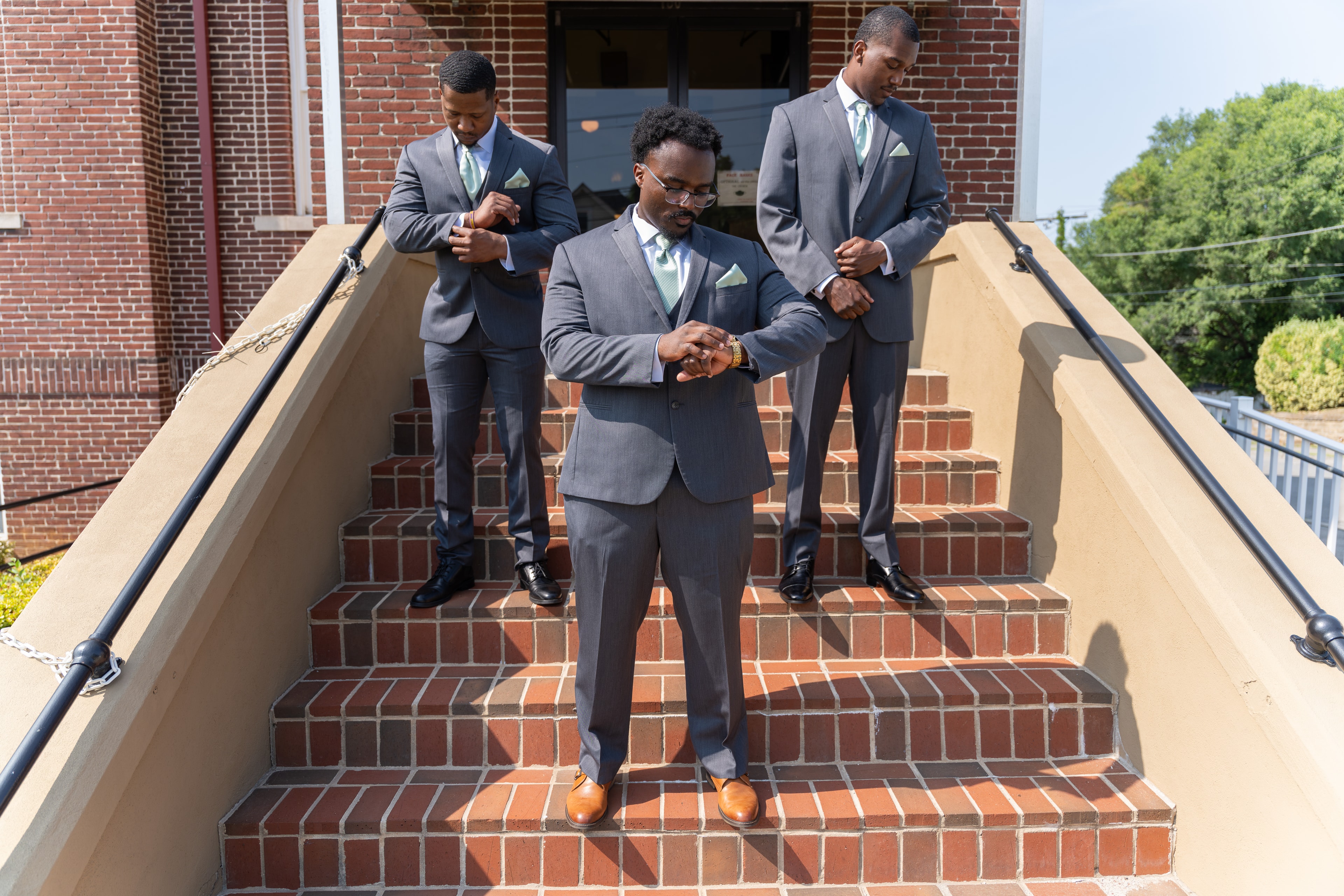 Groom and groomsmen on church steps adjusting suits