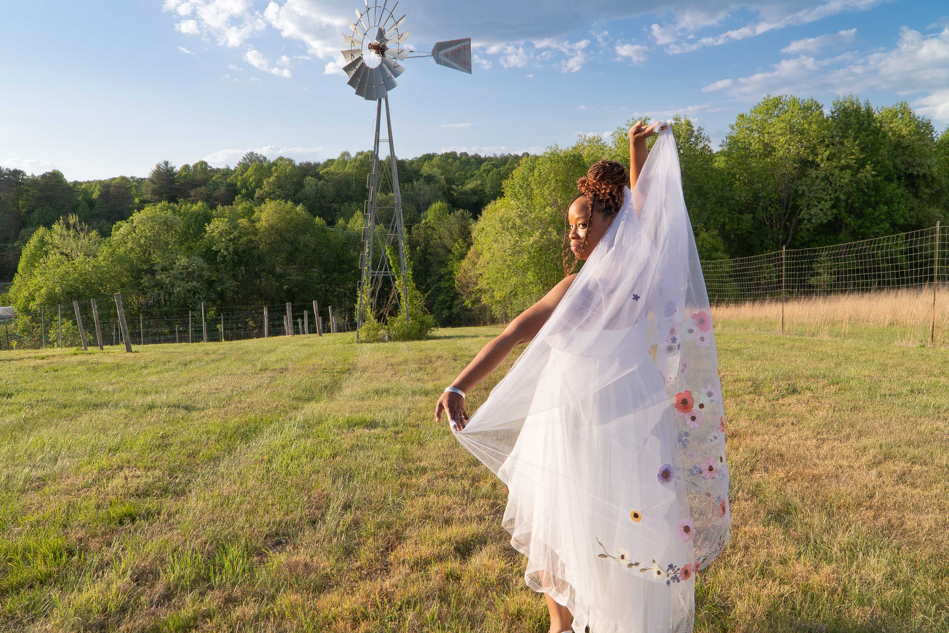 Bride lifting floral veil in golden field