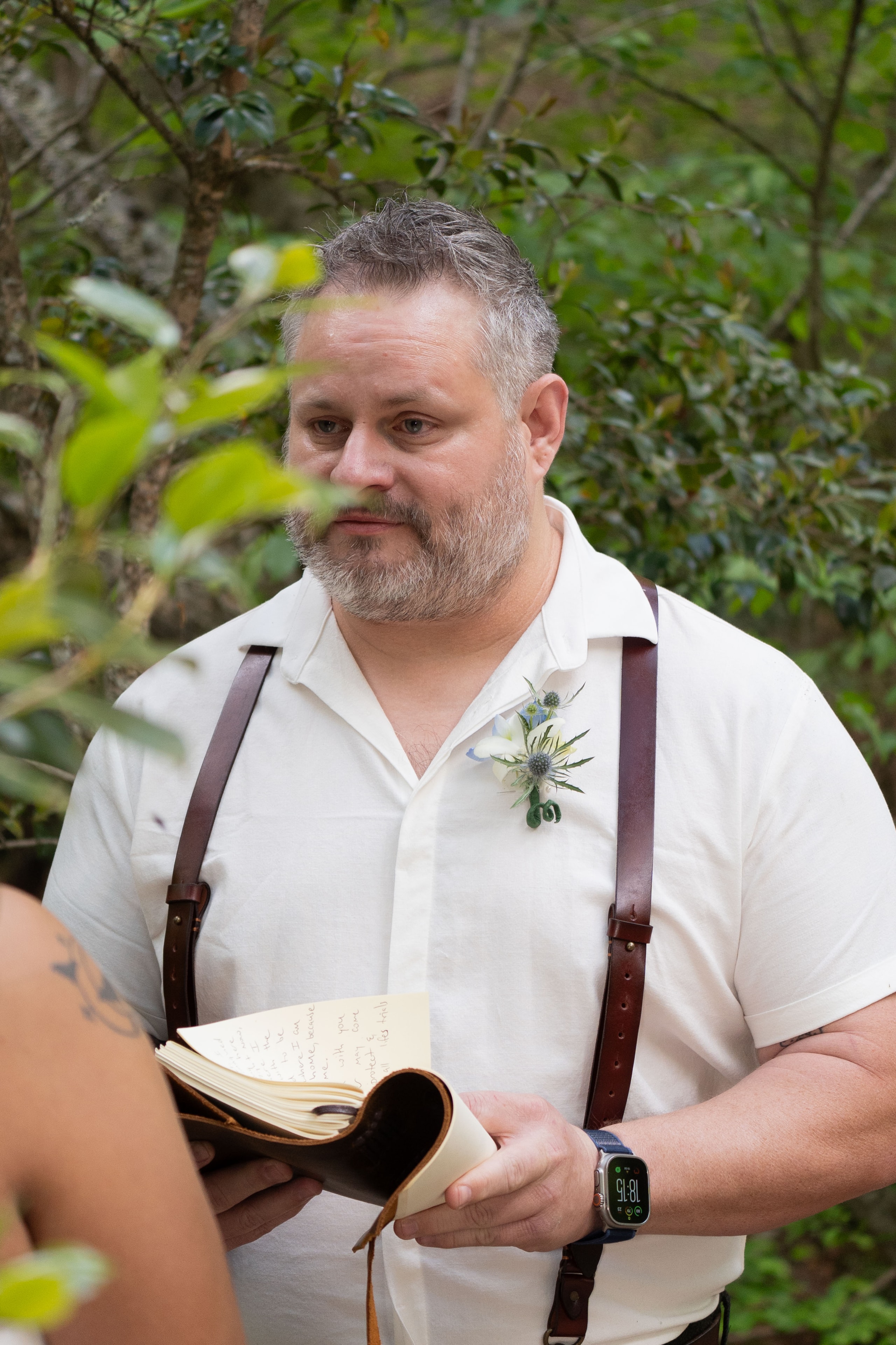 Groom reading handwritten vows from leather journal