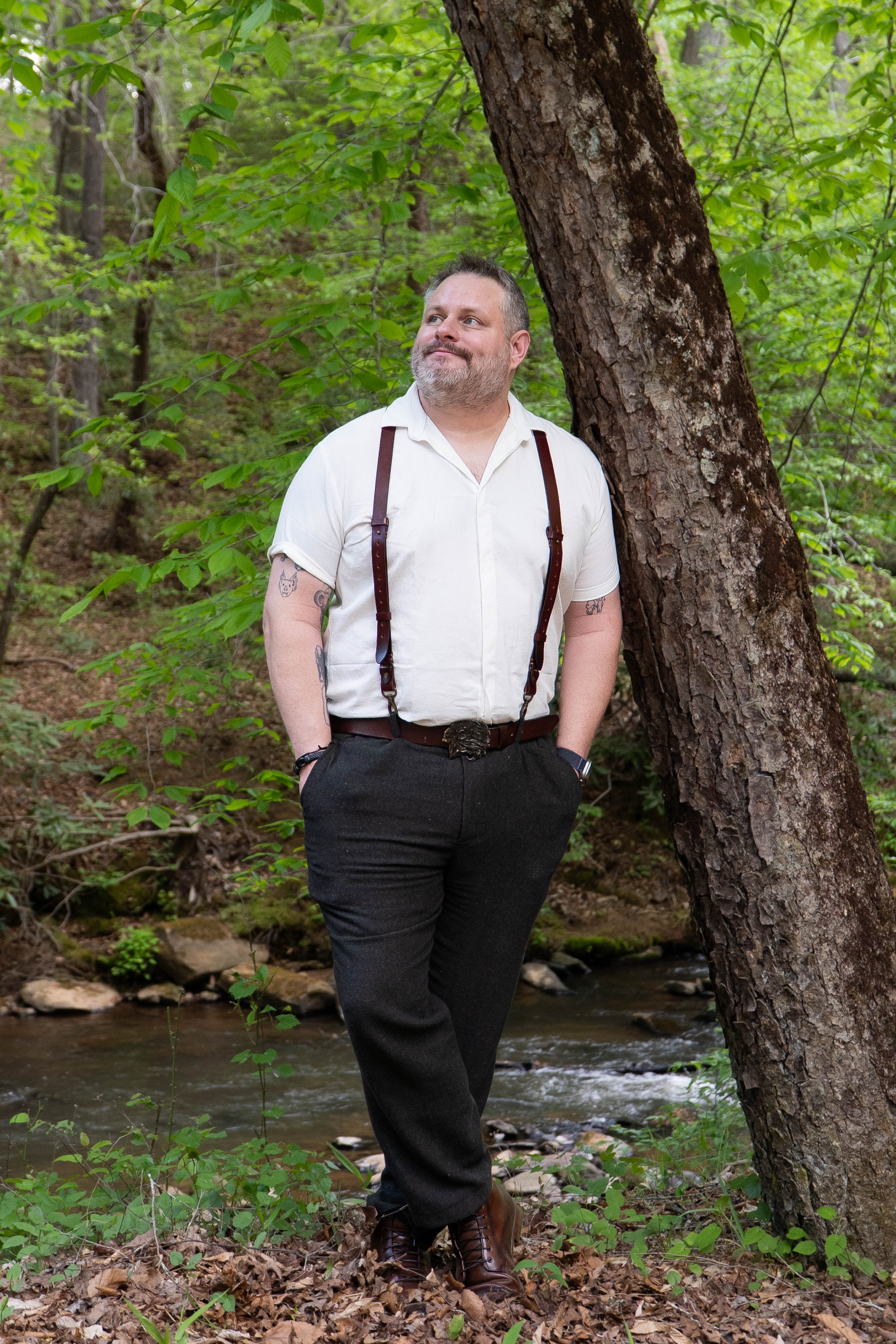 Groom portrait by the creek in suspenders