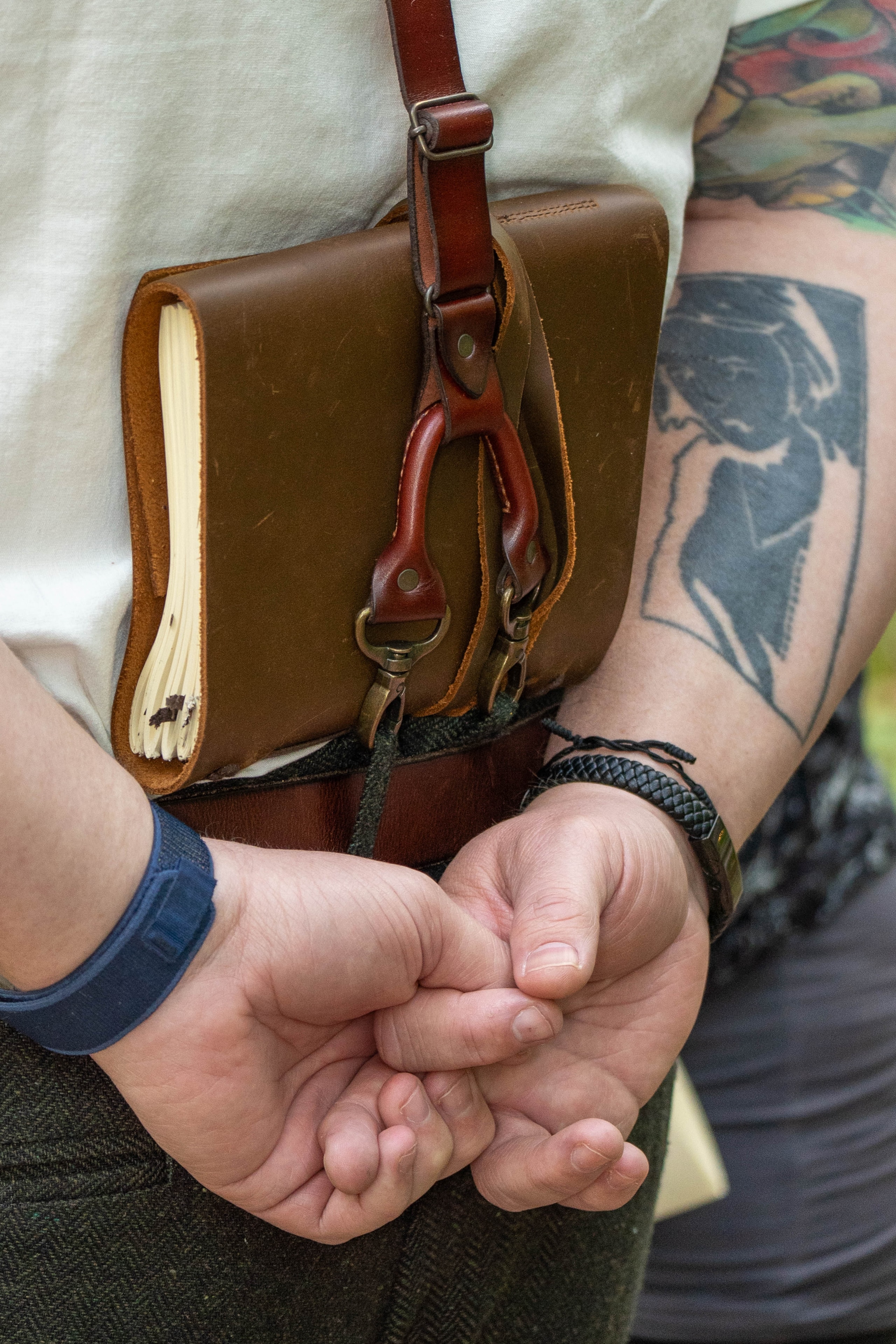 Close detail of leather satchel and clasped hands