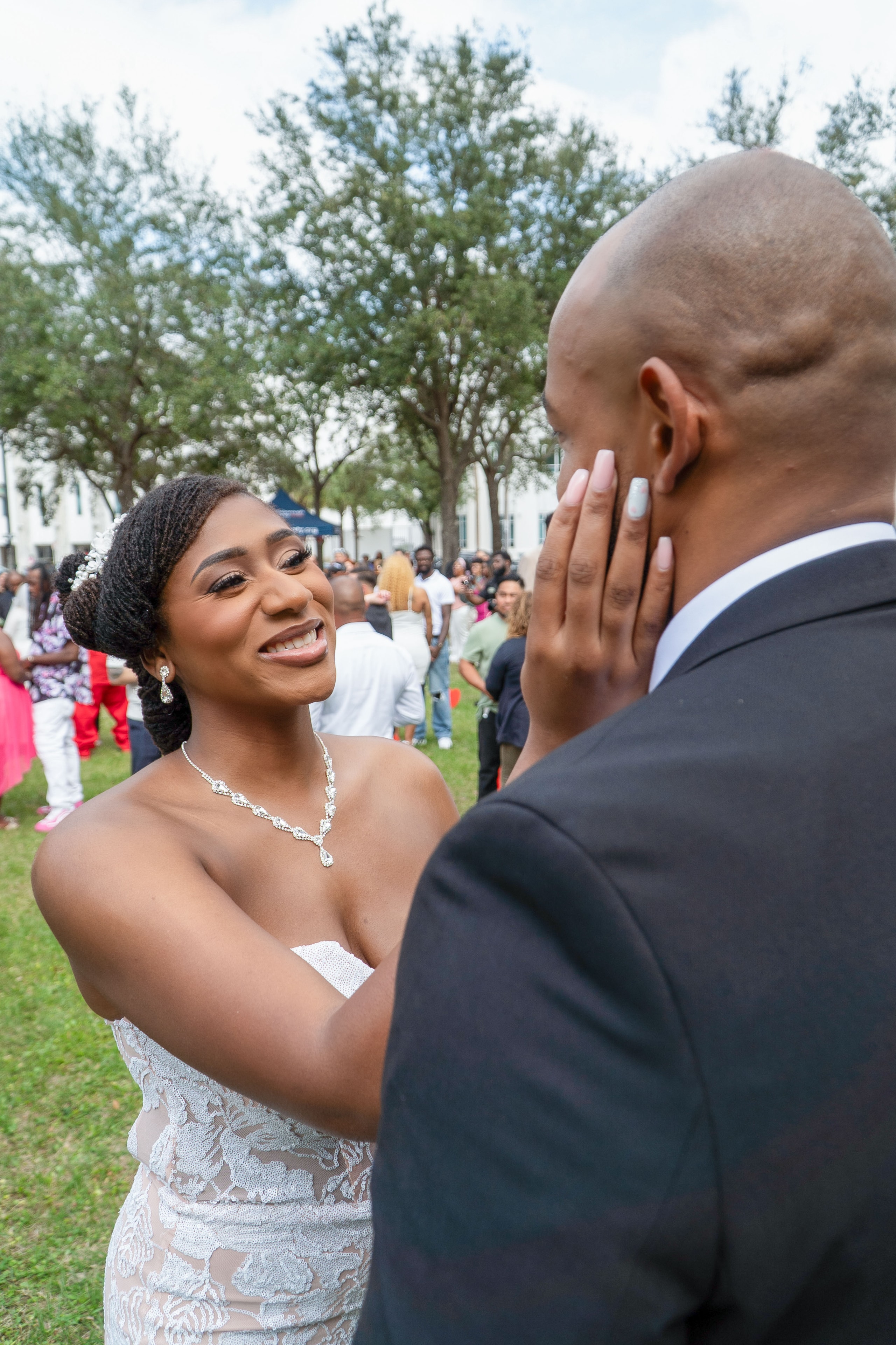 Bride laughing and touching groom's face during outdoor wedding celebration