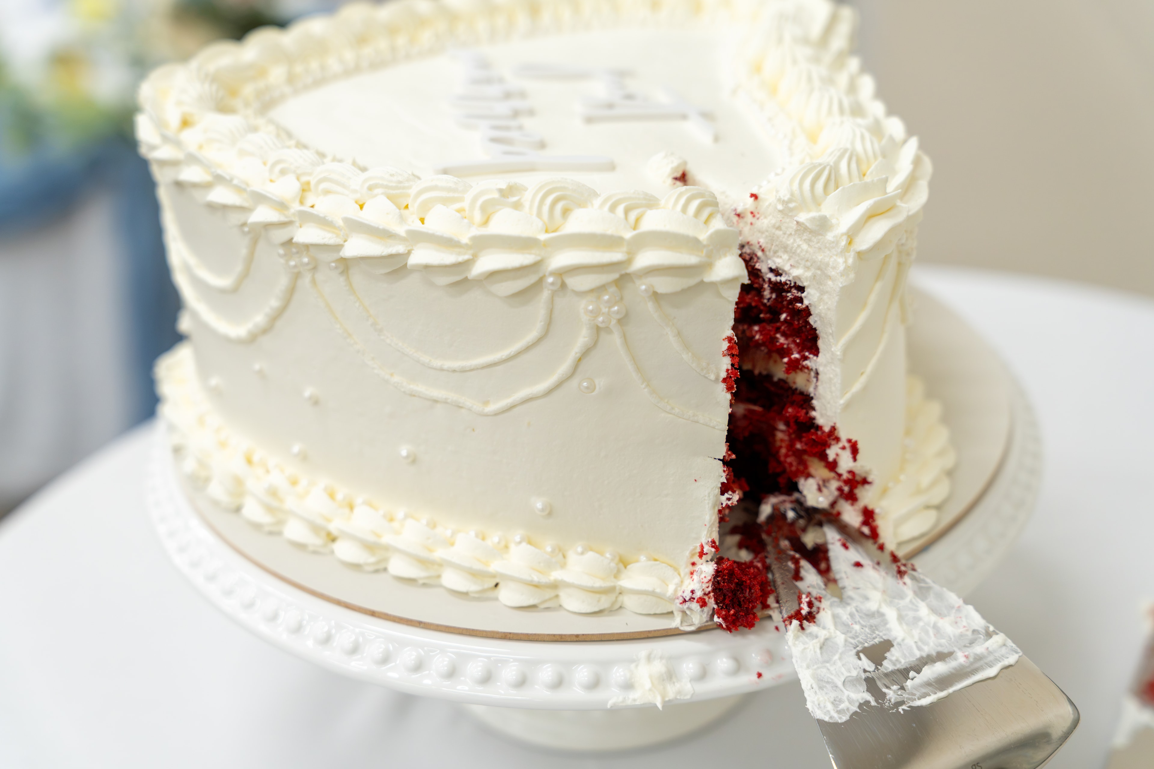 Red velvet wedding cake being cut with a lace-wrapped knife