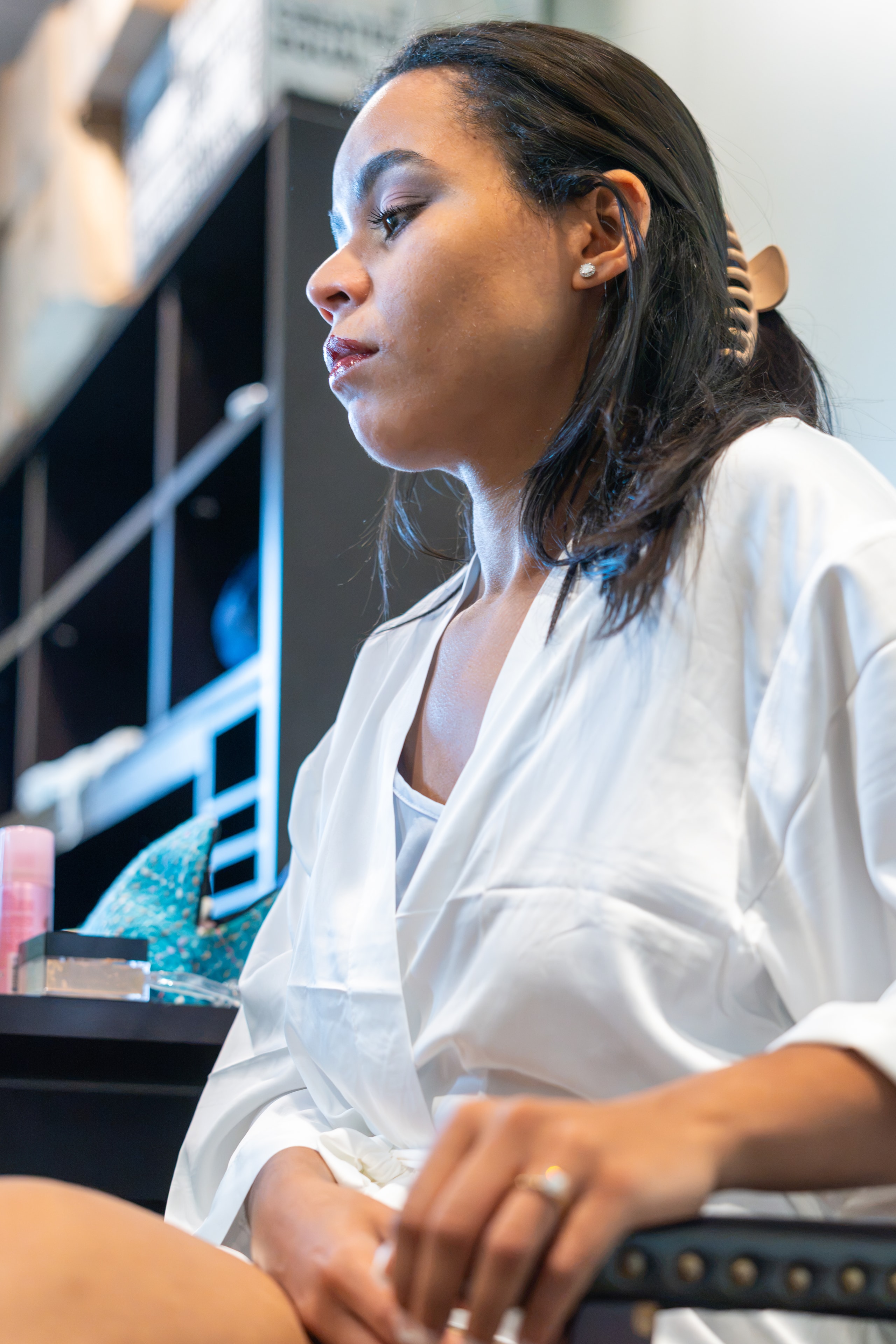 Bride in white robe sitting quietly during hair and makeup