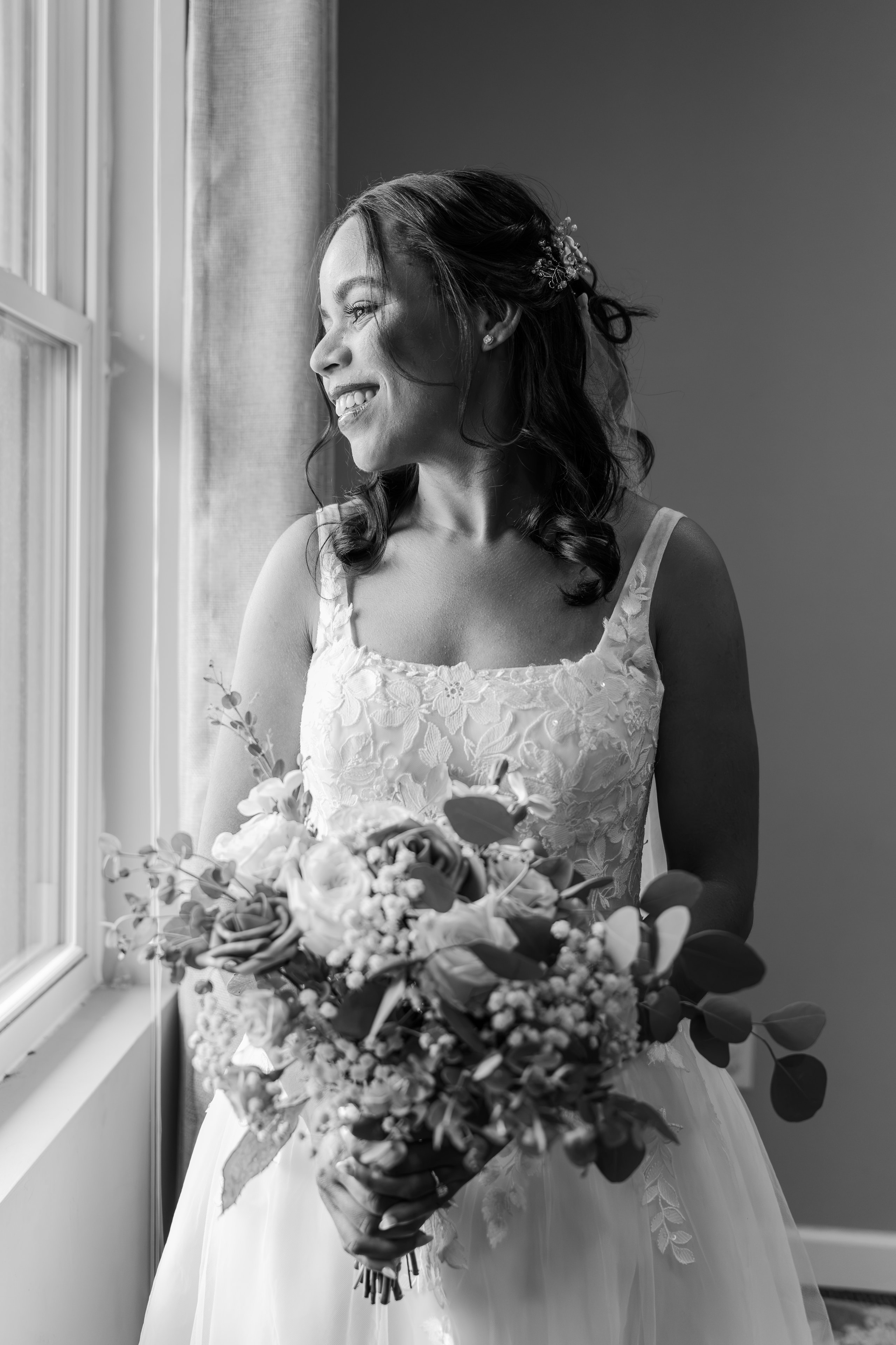 Bride in black and white holding bouquet by window light